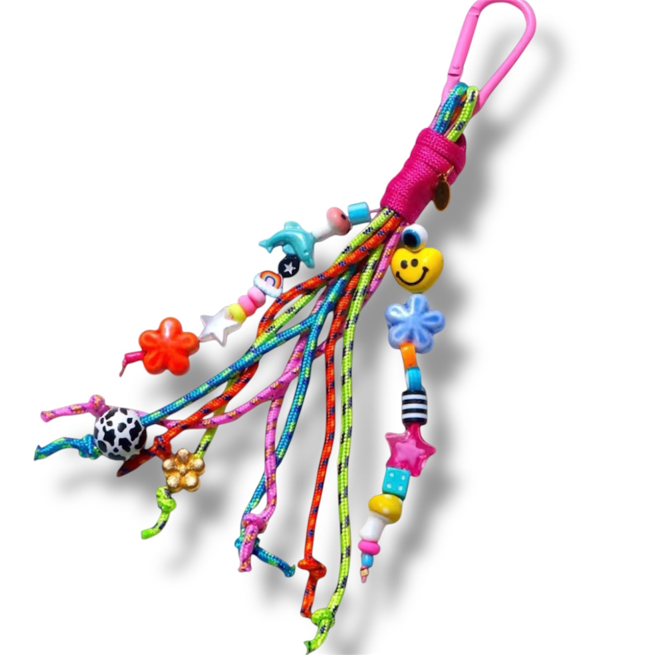 Colorful handmade bag charm with cords and beaded details clipped to a tote bag