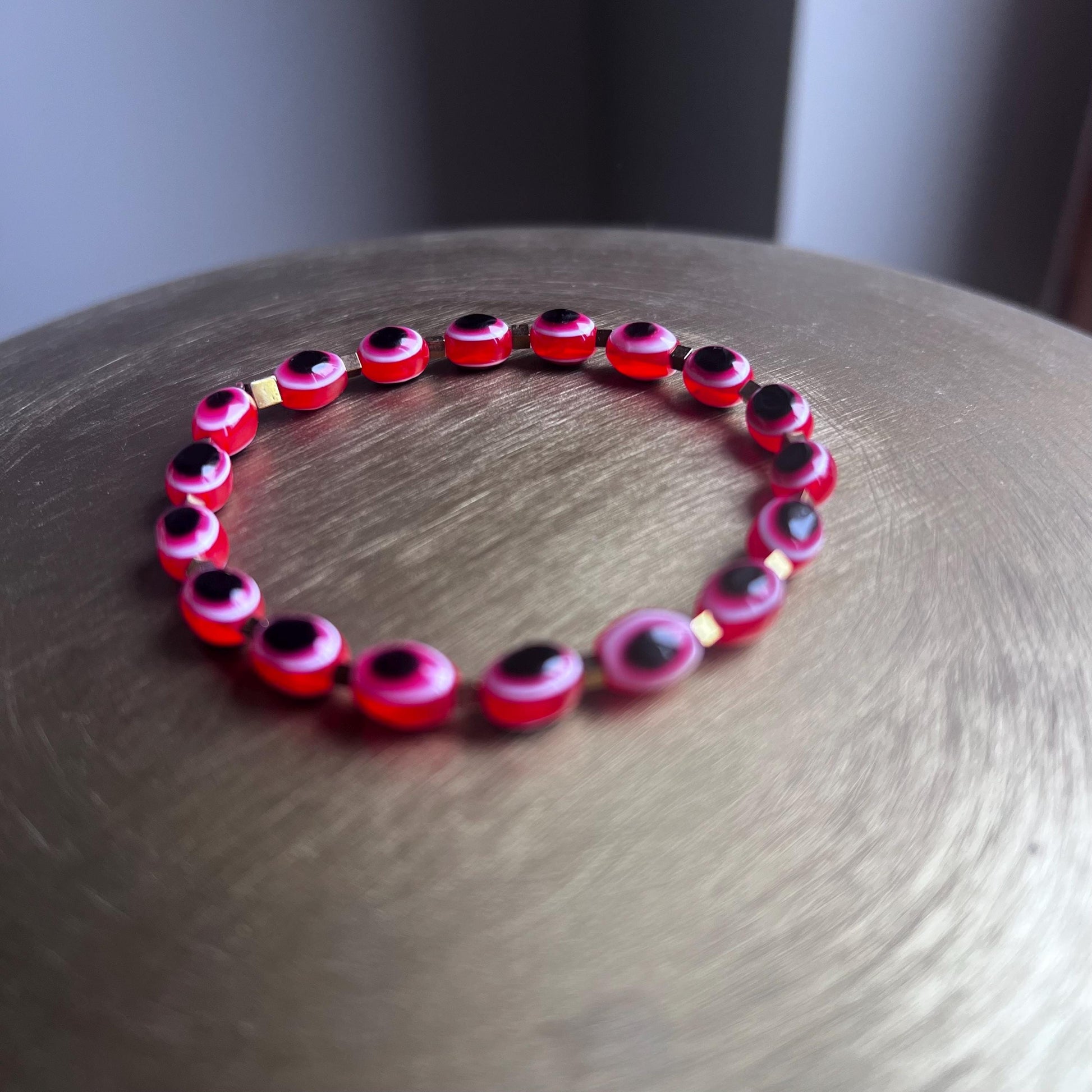 Close-up of evil eye charm on lipstick red protection bracelet - detailed spiritual jewelry