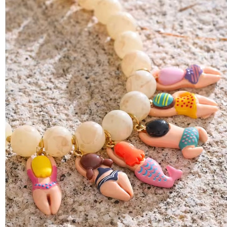 Close-up of Beach Babe charm necklace featuring starfish, beads, and shell accents