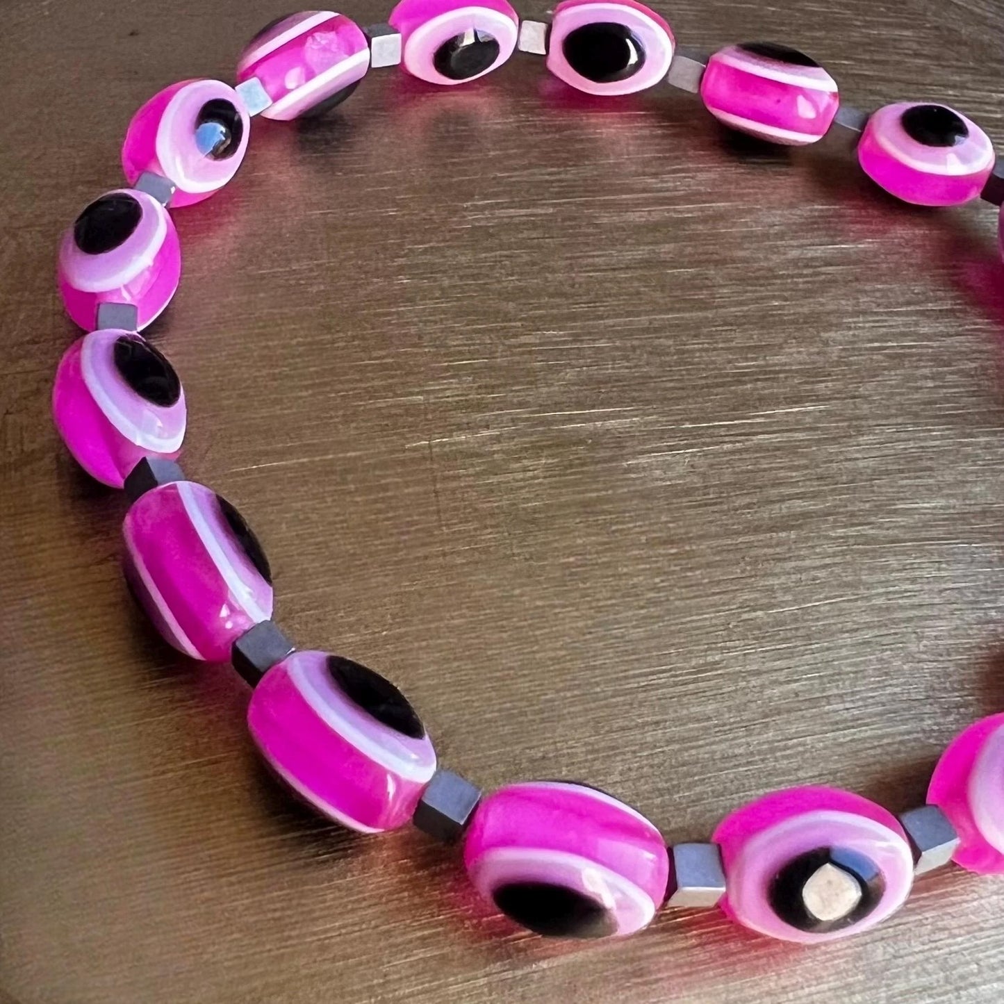 Close-up of pink evil eye beads on stretchy protection bracelet