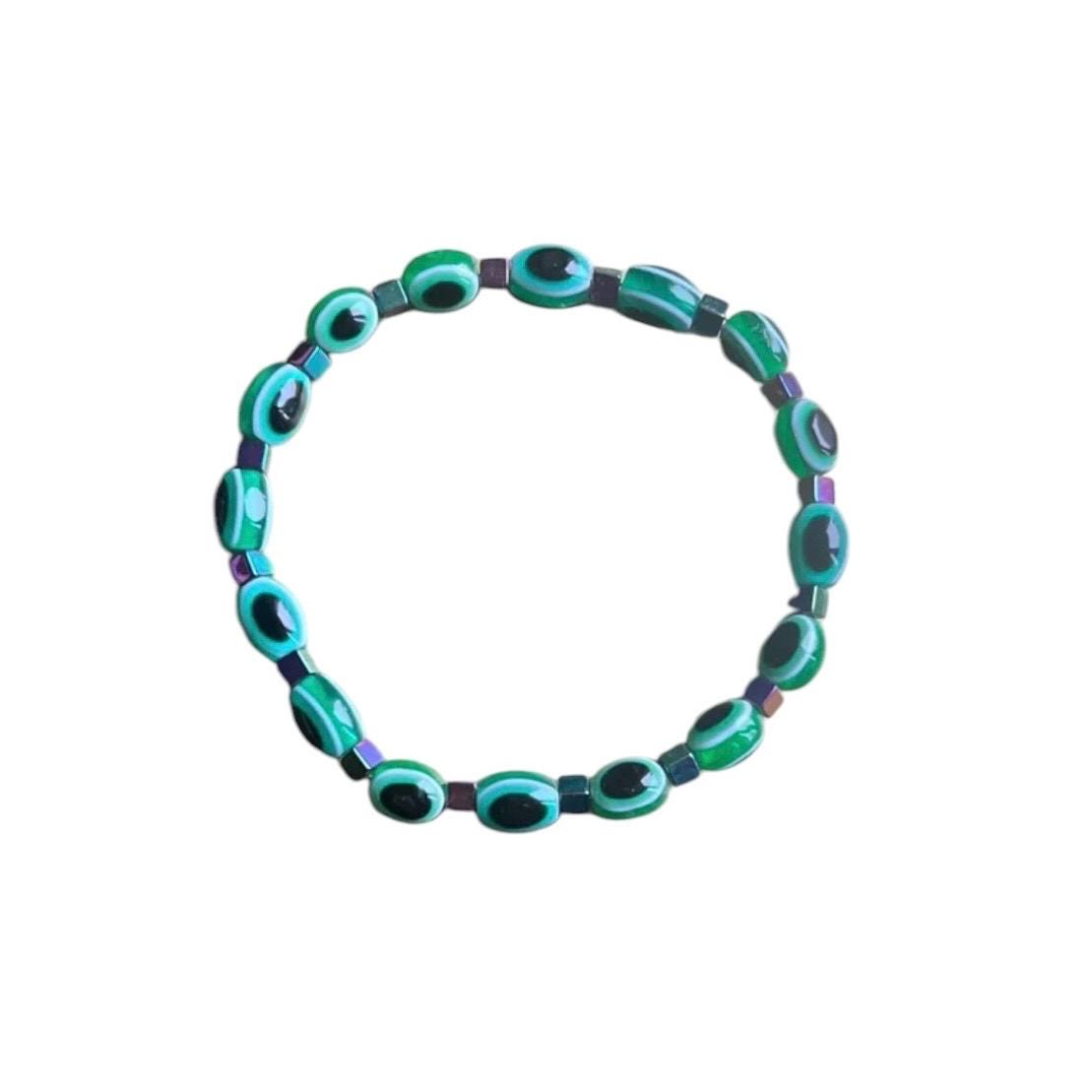 Emerald green evil eye bracelet flat lay - elegant spiritual protection accessory